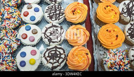Cupcake with Buttercream Frosting. Top view of colorful cupcakes with swirled frosting, with whipped cream and sprinkles on a tray. Stock Photo