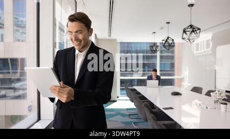 Confident young businessman smiling while working on digital tablet Stock Photo