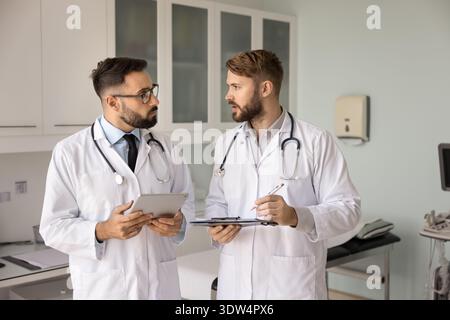 Medical discussion between two male doctors holding digital tablet clipboard Stock Photo