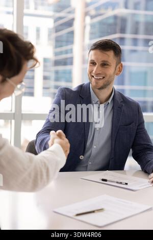 Two business partners signing contract, shaking hands, accomplishing negotiations Stock Photo