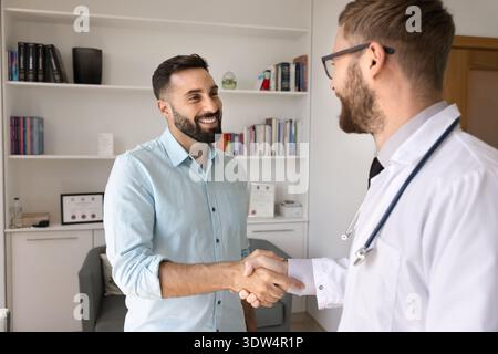 Two smiling young men doctor and pharma representative shake hands Stock Photo