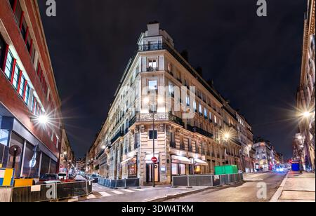 Night view of an illuminated classic Haussmannian corner building and streetlights at an empty city intersection in Paris, France. Stock Photo