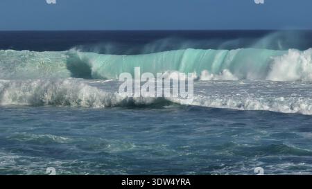Powerful ocean wave curling and breaking with white foam and spray, showing the dynamic energy of the sea in a beautiful turquoise and deep blue water. Natural seascape background. Nature landscape Stock Photo