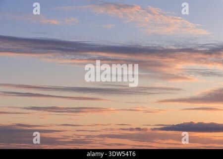 Sunset cloudscape with soft peach and lavender streaks across open sky, calm pastel tones layered clouds and wide copy space for background use in cre Stock Photo