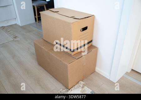 Cardboard moving boxes stacked on floor in minimalist home interior Stock Photo