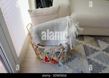 Woven rattan basket with cozy blankets and yarn in Scandinavian home interior Stock Photo
