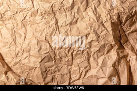 Brown crumpled kraft paper texture covers entire surface. Wrinkled sheet shows deep folds and irregular creases. Abstract background for packaging, cr Stock Photo