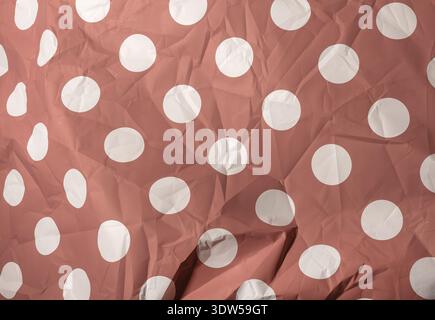 Red polka dot paper texture background. White circle pattern on crumpled surface. Retro decorative backdrop concept. Stock Photo
