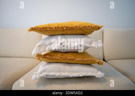Stack of decorative pillows on sofa in cozy Scandinavian living room Stock Photo