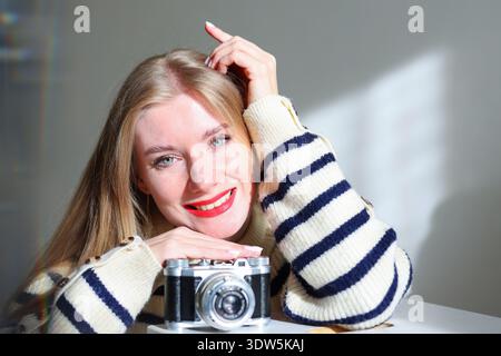 Bright portrait of young woman with classic film camera. Content creator, blogger and visual storytelling concept. Stock Photo