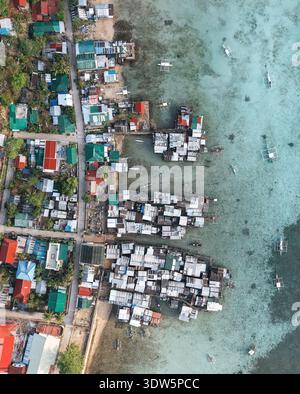 Aerial view of vibrant houses on the coast where the land meets the turquoise waters, Siargao, Philippines. Stock Photo