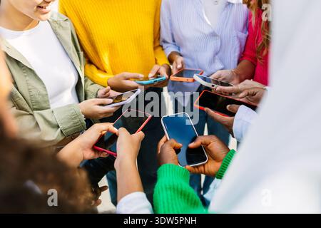 Group of diverse female friends using smartphones at city street Stock Photo