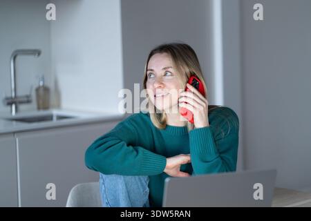 Pleasant phone call. Happy midlife woman chatting with cellphone comfort sits at home sharing news Stock Photo