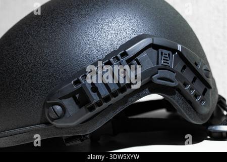Close-up view of a black tactical helmet featuring a modular side rail system for customization and equipment attachment Stock Photo