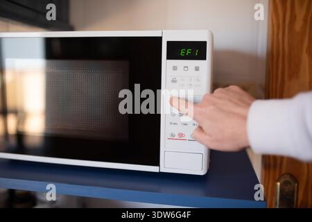 Close up of male hand pressing button on white microwave Stock Photo