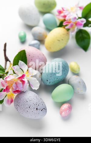Colorful pastel easter eggs arranged with delicate spring blossoms on a white background Stock Photo
