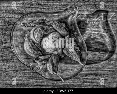 Black And White Dried Rosebuds On Glass Pitcher Over Textured Wood Surface, High Contrast Shadows, Grainy Film Effect, Intimate Macro Framing Conveyin Stock Photo
