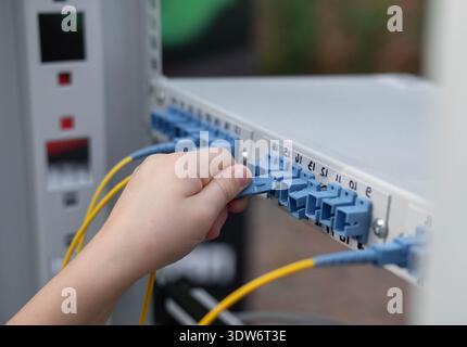 Close up child's hand plugs the cable into the connector. Training stand at an exhibition of professions. Blur and selective focus Stock Photo
