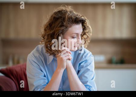 Pensive sensitive woman sadly looks down suffering from anxiety, heartbreak, chronic mental fatigue. Stock Photo