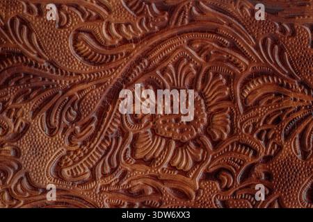 Dark brown red old cracked  leather with floral print. Sample of rough leather with ornament. Vintage style. Stock Photo