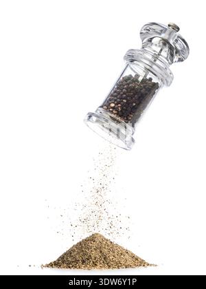 Black peppercorns are ground and fall into powder, isolated on white background. Stock Photo