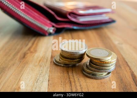 Red leather partmone and coins stack on the wood table. Wallet with european money for commerce business concept. Stock Photo