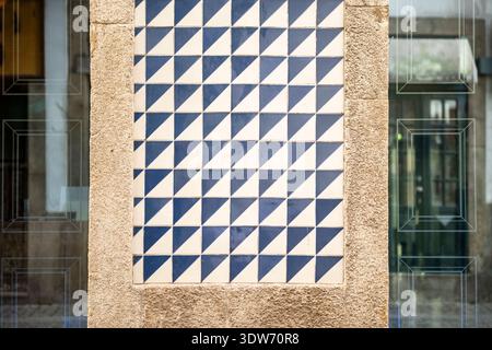 Close-up of traditional Portuguese azulejo tiles in Porto, Portugal, featuring a geometric blue-and-white pattern framed by textured stone and reflect Stock Photo