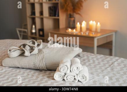 Cozy spa setting with candlelight and towels on bed in relaxing atmosphere Stock Photo