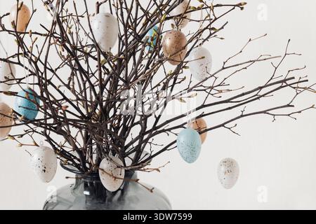 Pastel Easter eggs on decorative spring tree branches Stock Photo