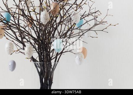 Easter branches with hanging speckled eggs in glass vase Stock Photo