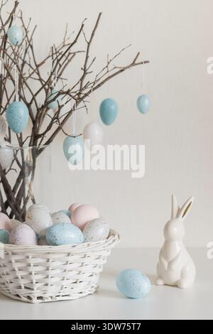 Easter tree with pastel eggs in vase and white bunny figurine vertical Stock Photo
