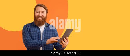 Man Using Tablet Standing Against Bright Yellow Background With Simple Design Patterns Stock Photo