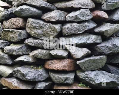 Piles of river stones in random shapes but still neat with a few small plants growing between them Stock Photo