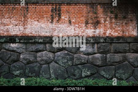 The surrounding wall of Kyū-Iwasaki-tei Garden juxtaposes traditional Japanese cut stone, reminiscent of castle fortifications, with red brick introdu Stock Photo