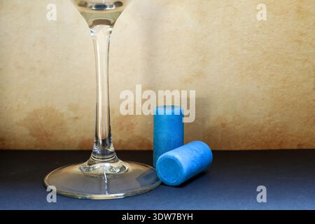 still life of synthetic blue wine corks next to an empty wine glass, symbolizing modern packaging solutions in the beverage industry Stock Photo