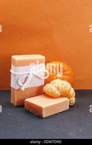 Handmade tangerine soap bars paired with fresh mandarin fruit in a bold studio setup, ideal for spa branding and organic beauty campaigns Stock Photo