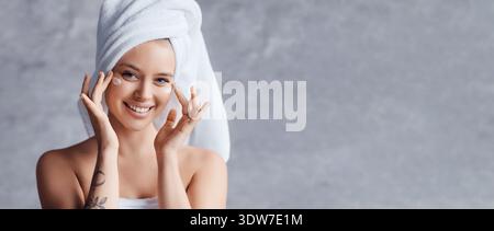 Woman Smiling With a Towel on Her Head in a Minimal Background While Showing Her Face Stock Photo