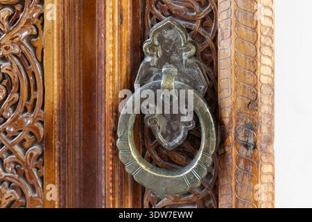 Ancient brass door handle mounted on an aged wooden door, showcasing intricate vintage metalwork and classic decorative hardware details that evoke hi Stock Photo