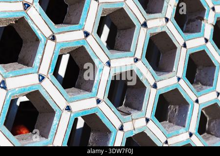 Close-up of a turquoise and white hexagonal tile lattice featuring repeating geometric patterns and honeycomb openings, creating a decorative, texture Stock Photo