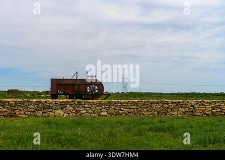 Old winnowing machine on a stone wall in a rural area of Palencia Stock Photo