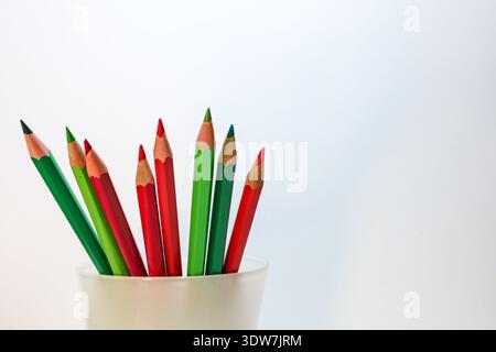 Red and green colored pencils arranged in a white cup against a clean background, symbolizing contrast, choice, balance, and creative thinking. Stock Photo