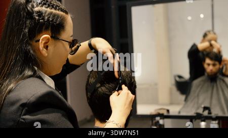 Barber using scissors and comb to style male haircut Stock Photo