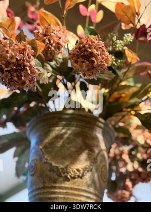 Dried hydrangea flowers arranged in a textured ceramic vase with swirl pattern, photographed as an autumn still life. Stock Photo