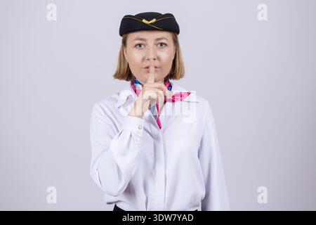 Female pilot in uniform showing silence gesture with finger Stock Photo