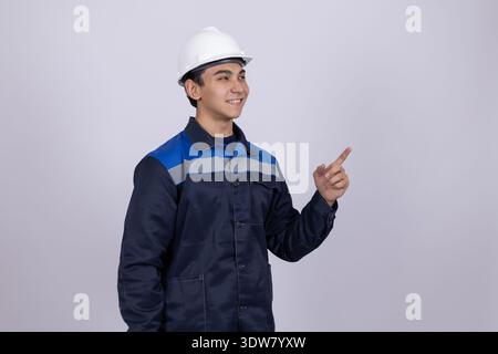 Construction worker pointing aside and looking at camera Stock Photo