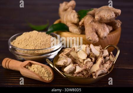 Fresh ginger root, dried ginger and ginger powder on a dark wooden background. Stock Photo