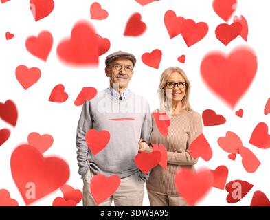 Happy mature couple standing under falling hearts isolated on white background Stock Photo