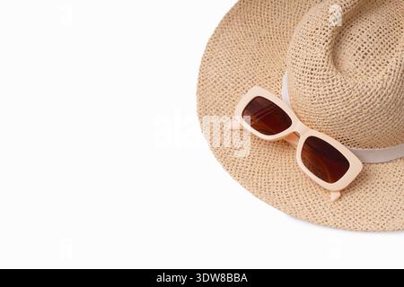 A straw hat and a pair of sunglasses rest on a clean white surface. The setting suggests it is indoors during the daytime. The items are ready for out Stock Photo