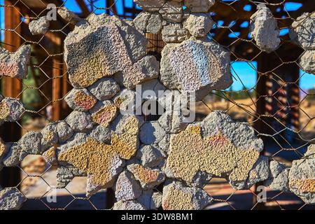 Abandoned Concrete Wall Texture and Wire Mesh in Sunlit Desert Structure Stock Photo