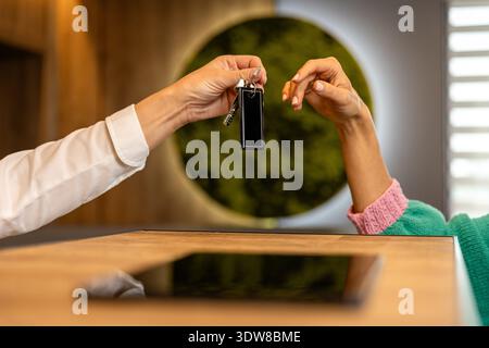 Hotel receptionist handing room key to guest at reception desk close up Stock Photo
